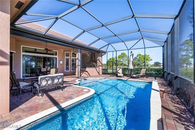 view of swimming pool with a patio, glass enclosure, and ceiling fan