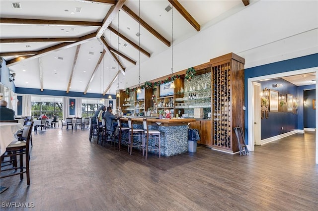 bar with hanging light fixtures, beamed ceiling, dark wood-type flooring, and high vaulted ceiling