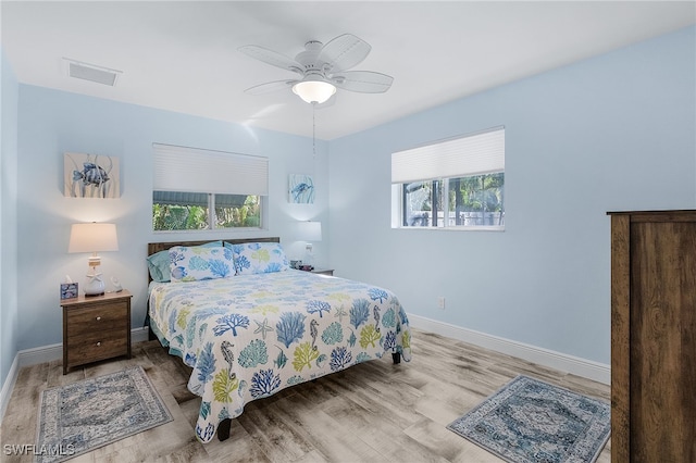 bedroom featuring ceiling fan, light hardwood / wood-style floors, and multiple windows