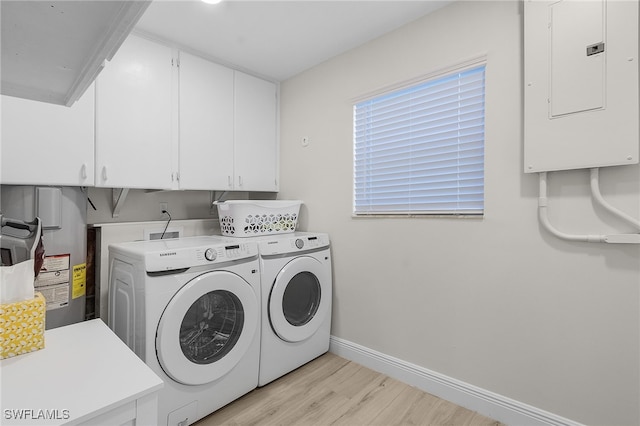 washroom with cabinets, electric panel, washing machine and dryer, water heater, and light hardwood / wood-style floors