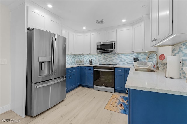 kitchen with blue cabinetry, white cabinetry, sink, stainless steel appliances, and light hardwood / wood-style floors