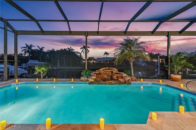 pool at dusk with a patio area and a lanai