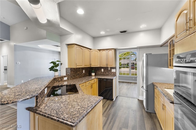 kitchen featuring dark hardwood / wood-style floors, dark stone countertops, light brown cabinetry, appliances with stainless steel finishes, and kitchen peninsula