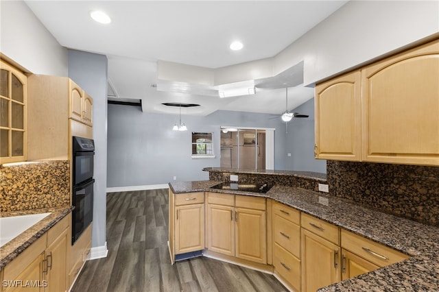 kitchen with light brown cabinetry, ceiling fan with notable chandelier, and dark stone counters