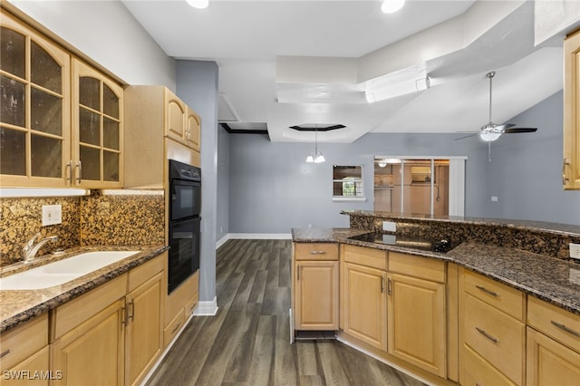 kitchen featuring light brown cabinetry, dark hardwood / wood-style flooring, dark stone counters, black appliances, and sink