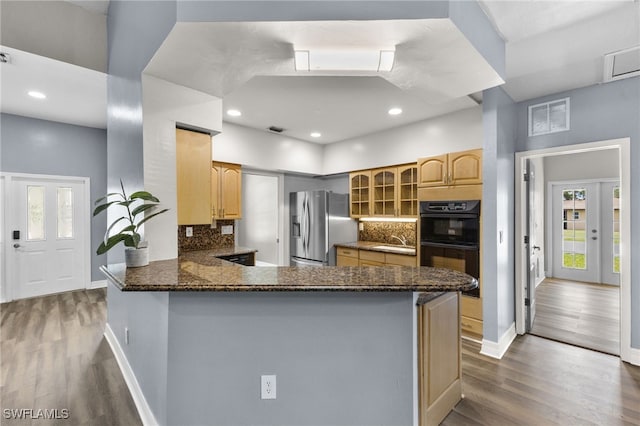 kitchen with kitchen peninsula, stainless steel fridge, backsplash, and black double oven