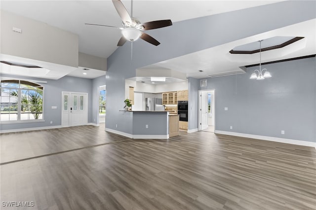 unfurnished living room with dark hardwood / wood-style flooring, a towering ceiling, and ceiling fan with notable chandelier