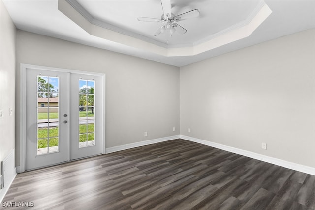 spare room featuring a tray ceiling, ceiling fan, french doors, and dark wood-type flooring