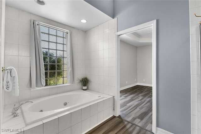 bathroom featuring a relaxing tiled tub, a healthy amount of sunlight, wood-type flooring, and ornamental molding