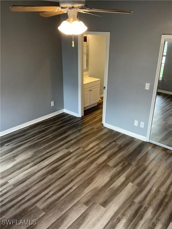 unfurnished bedroom with connected bathroom, ceiling fan, and dark wood-type flooring