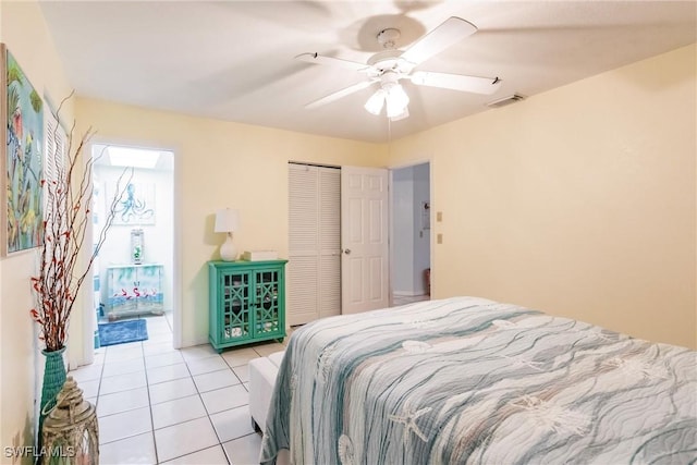 bedroom with ceiling fan, light tile patterned floors, and a closet