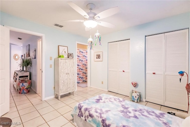 bedroom with ceiling fan, light tile patterned floors, and multiple closets