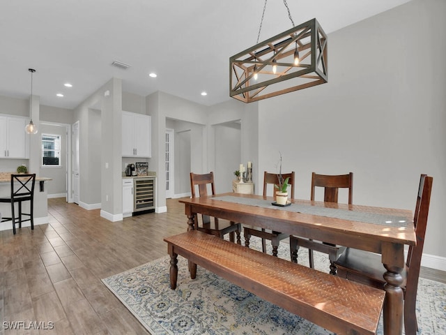 dining area with dark wood-style floors, beverage cooler, visible vents, and baseboards