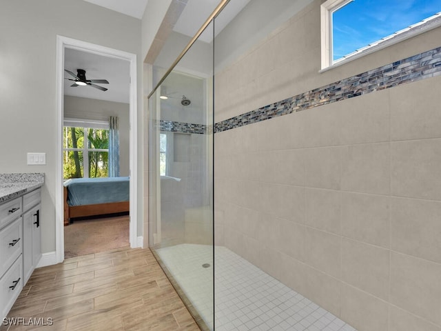 ensuite bathroom with a walk in shower, ensuite bathroom, wood finish floors, vanity, and baseboards