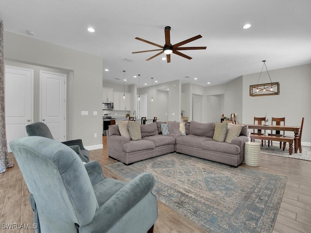 living room featuring recessed lighting, baseboards, and light wood finished floors