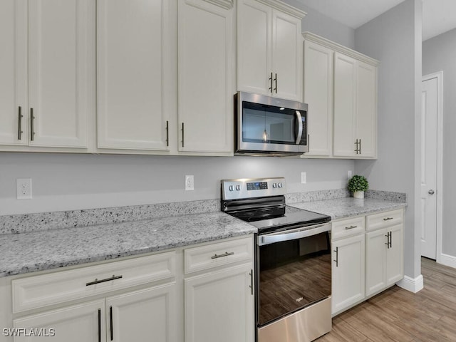 kitchen featuring light stone counters, white cabinetry, baseboards, light wood-style floors, and appliances with stainless steel finishes