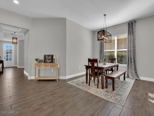 dining area featuring dark wood-type flooring, plenty of natural light, an inviting chandelier, and baseboards