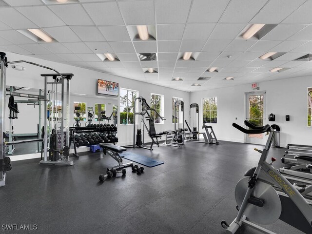 exercise room with a paneled ceiling, visible vents, and baseboards