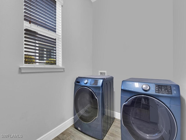 clothes washing area featuring wood finished floors, laundry area, baseboards, and separate washer and dryer