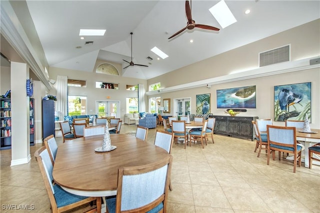 tiled dining area featuring ceiling fan, high vaulted ceiling, and a skylight