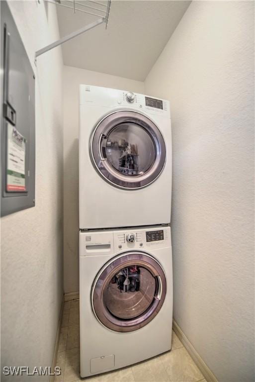 clothes washing area featuring stacked washer / drying machine and light tile patterned flooring