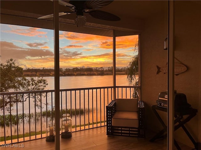 sunroom featuring a water view and ceiling fan