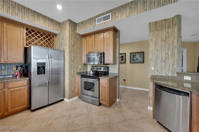 kitchen with tasteful backsplash, stone counters, light tile patterned floors, and appliances with stainless steel finishes