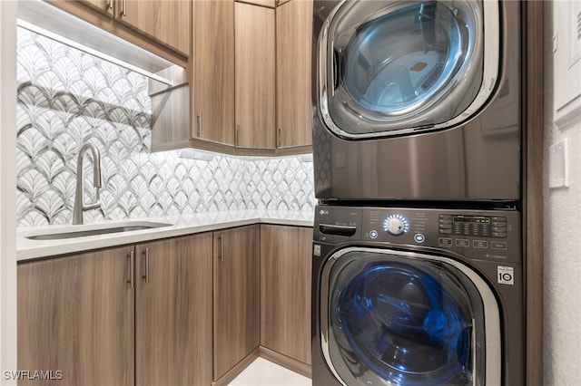 washroom featuring cabinets, sink, and stacked washer / dryer