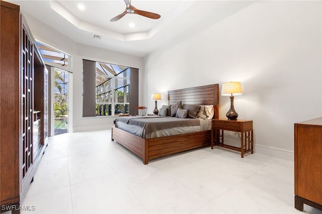 bedroom with ceiling fan, access to exterior, and a raised ceiling