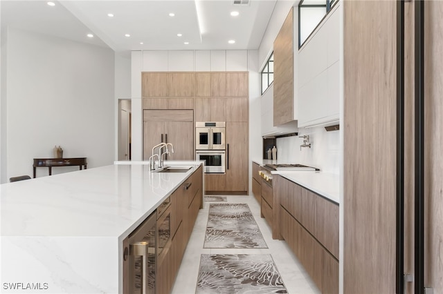 kitchen featuring white cabinetry, appliances with stainless steel finishes, wine cooler, a large island with sink, and sink