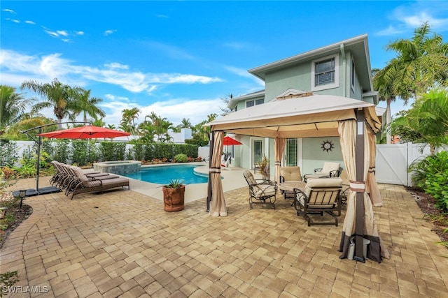 exterior space with a fenced backyard, a pool with connected hot tub, a gazebo, stucco siding, and a patio area