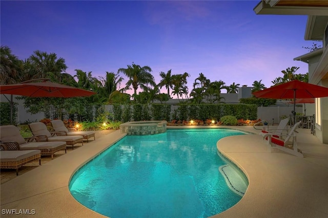 pool at dusk with a patio, a fenced backyard, and a pool with connected hot tub