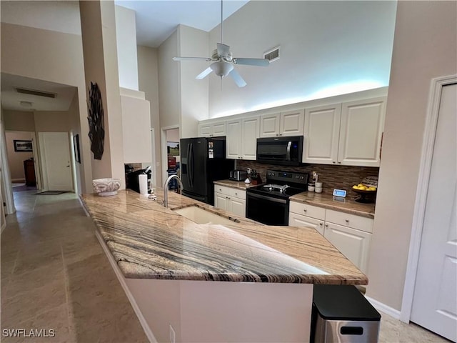 kitchen featuring black appliances, white cabinets, sink, a towering ceiling, and kitchen peninsula