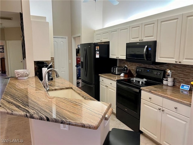 kitchen with white cabinets, black appliances, and a high ceiling