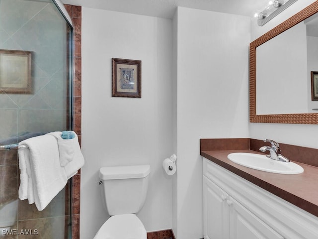 bathroom with vanity, a shower with shower door, and toilet