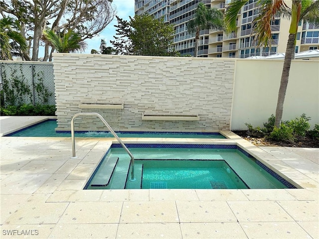 view of swimming pool with a community hot tub, fence, and a patio