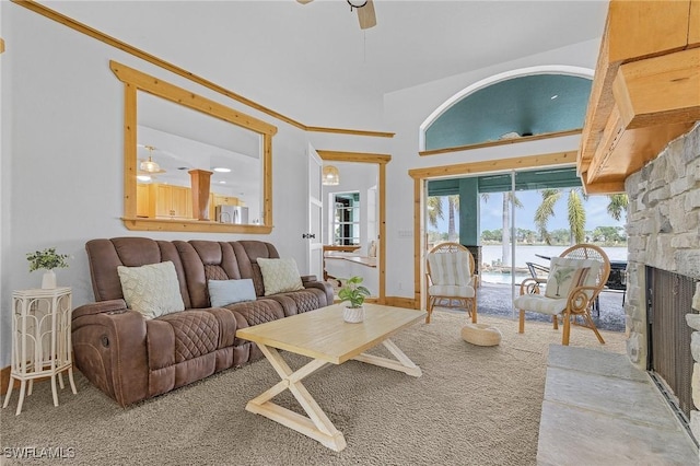 living room featuring ceiling fan, carpet, a towering ceiling, a fireplace, and a water view