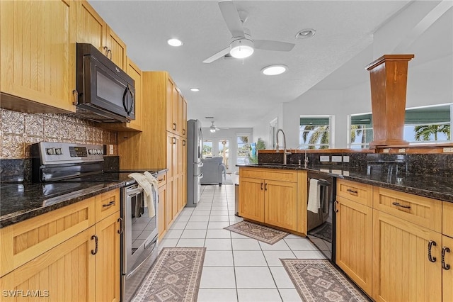 kitchen with black appliances, sink, dark stone countertops, tasteful backsplash, and light tile patterned flooring