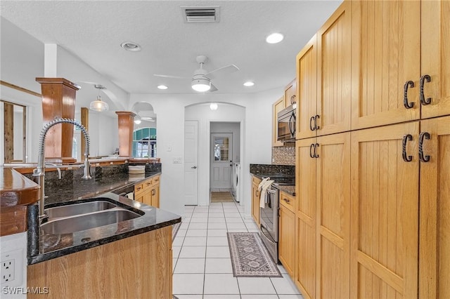 kitchen featuring arched walkways, appliances with stainless steel finishes, a ceiling fan, a sink, and separate washer and dryer