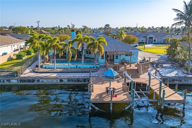 view of dock with boat lift, a swimming pool, fence, and a residential view