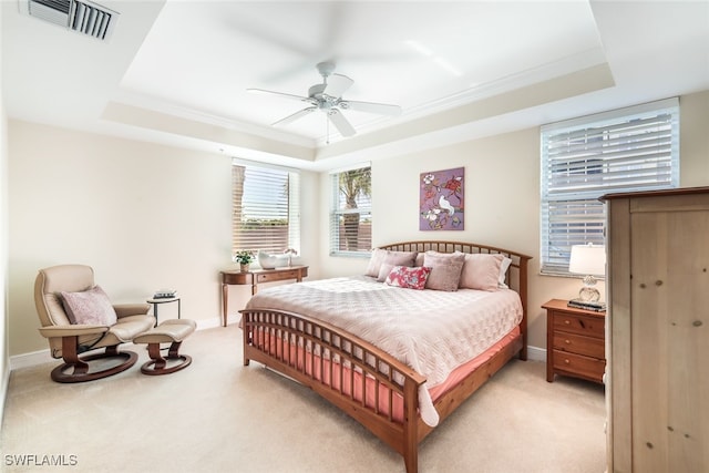 carpeted bedroom featuring a tray ceiling and ceiling fan