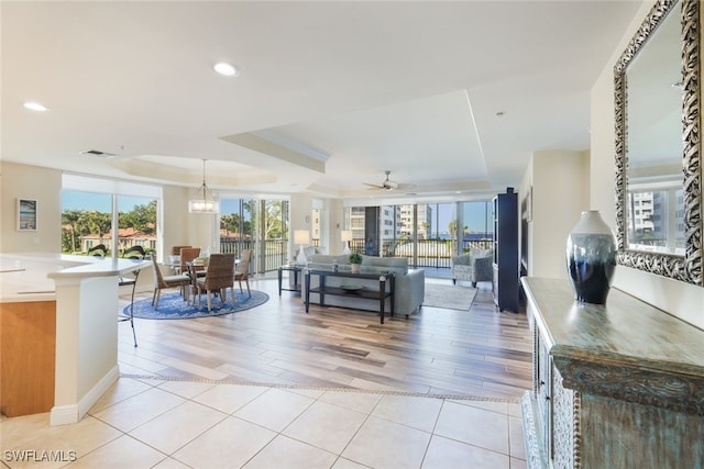 living room featuring a tray ceiling, ceiling fan, and light hardwood / wood-style flooring