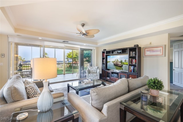 living room featuring ceiling fan, ornamental molding, and a tray ceiling