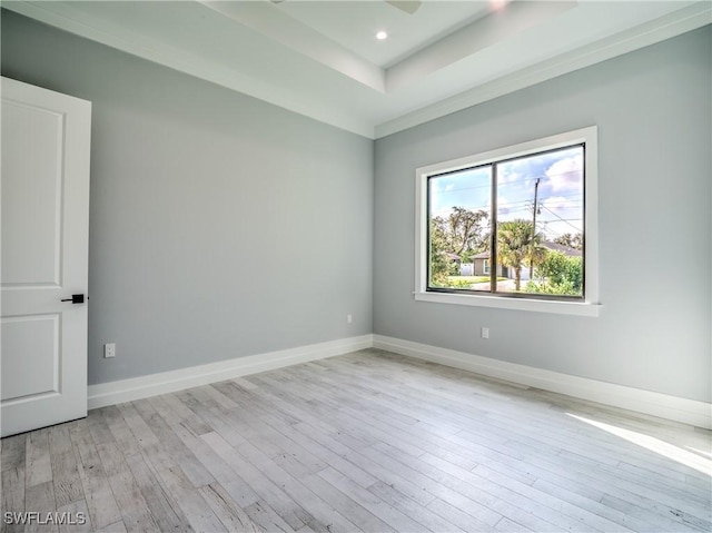 unfurnished room featuring light wood-type flooring and a tray ceiling