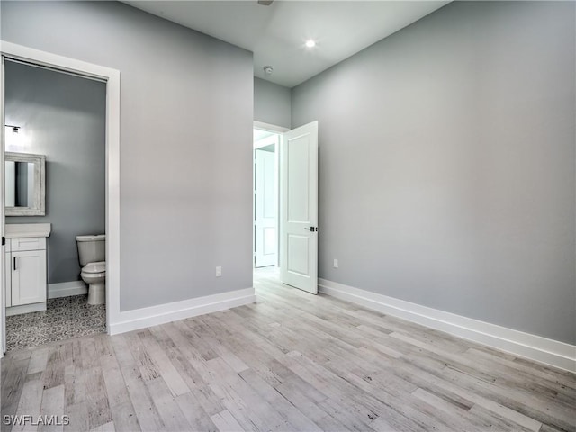 unfurnished bedroom with light wood-type flooring and ensuite bathroom