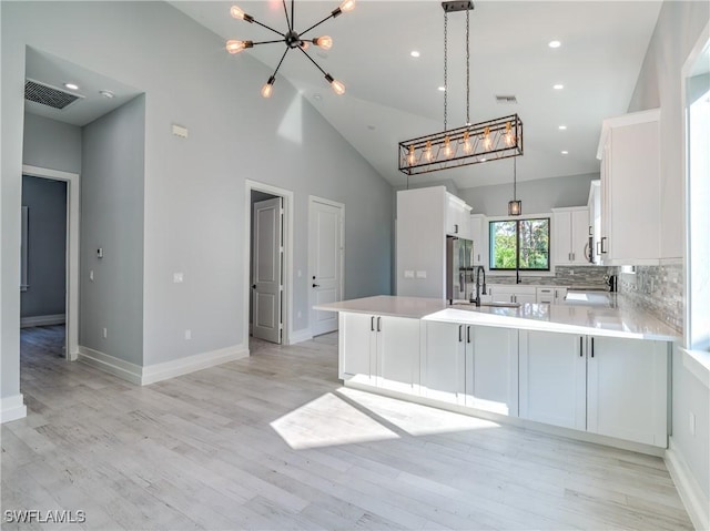 kitchen with kitchen peninsula, light hardwood / wood-style flooring, white cabinets, and pendant lighting