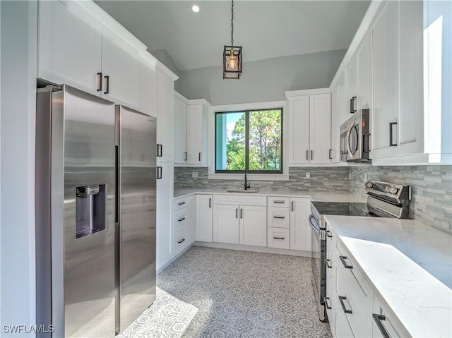 kitchen with light stone countertops, sink, vaulted ceiling, white cabinets, and appliances with stainless steel finishes