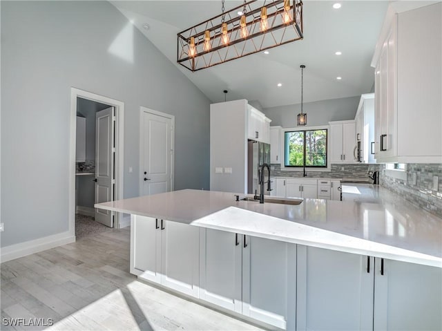 kitchen with white cabinetry, sink, hanging light fixtures, a kitchen breakfast bar, and kitchen peninsula