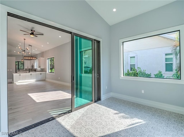 empty room with hardwood / wood-style floors, ceiling fan with notable chandelier, vaulted ceiling, and sink