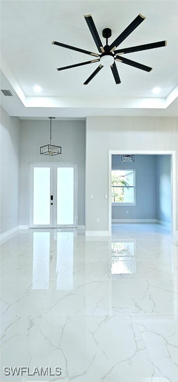 empty room with a raised ceiling, ceiling fan, and french doors